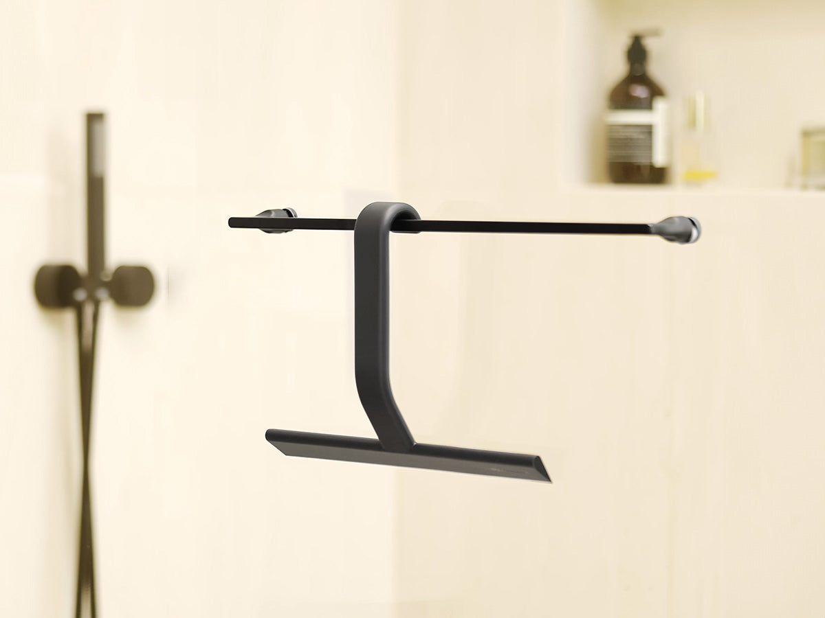 Black JustHang shower squeegee hanging from a shower rod by its built-in hook