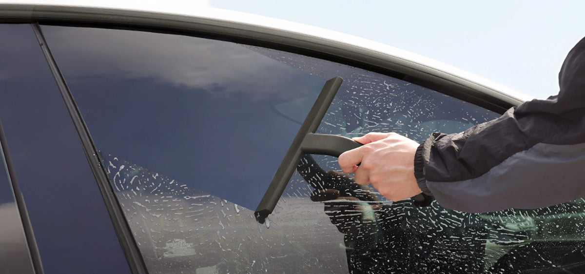 Black JustHang shower squeegee removing water from a car window