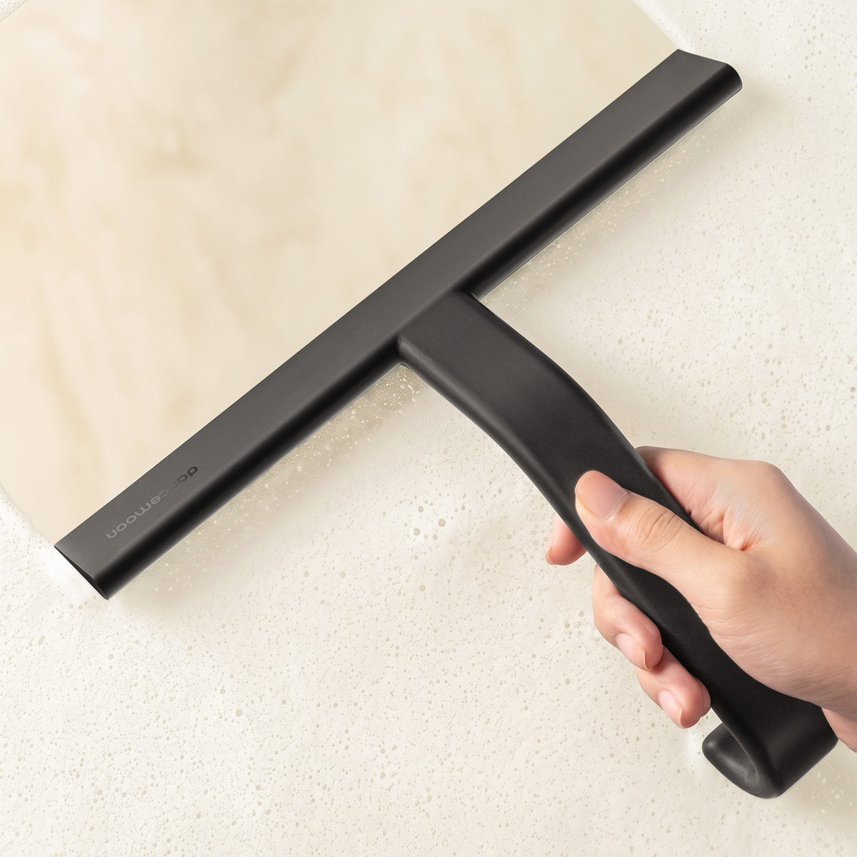 Black JustHang Wider squeegee removing water from a glass shower door